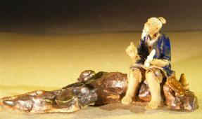 Miniature Ceramic Figurine Man Sitting On A Log - Blue Color